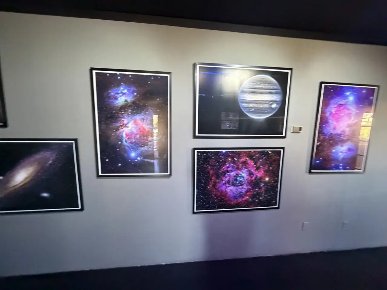 A wall of framed space photographs: nebulae, galaxies and Jupiter