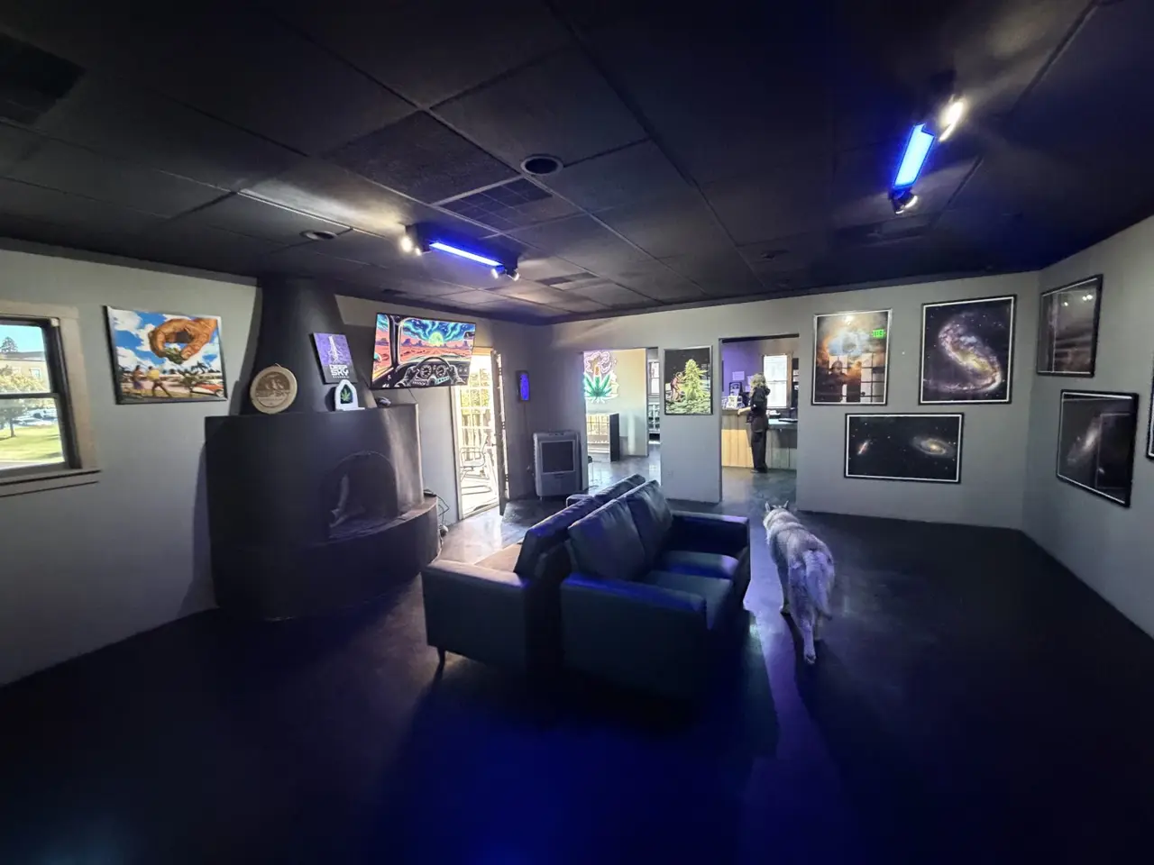 The lounge at Deep Sky Downtown: couches, a kiva fireplace and space art, with the shop through the doorway