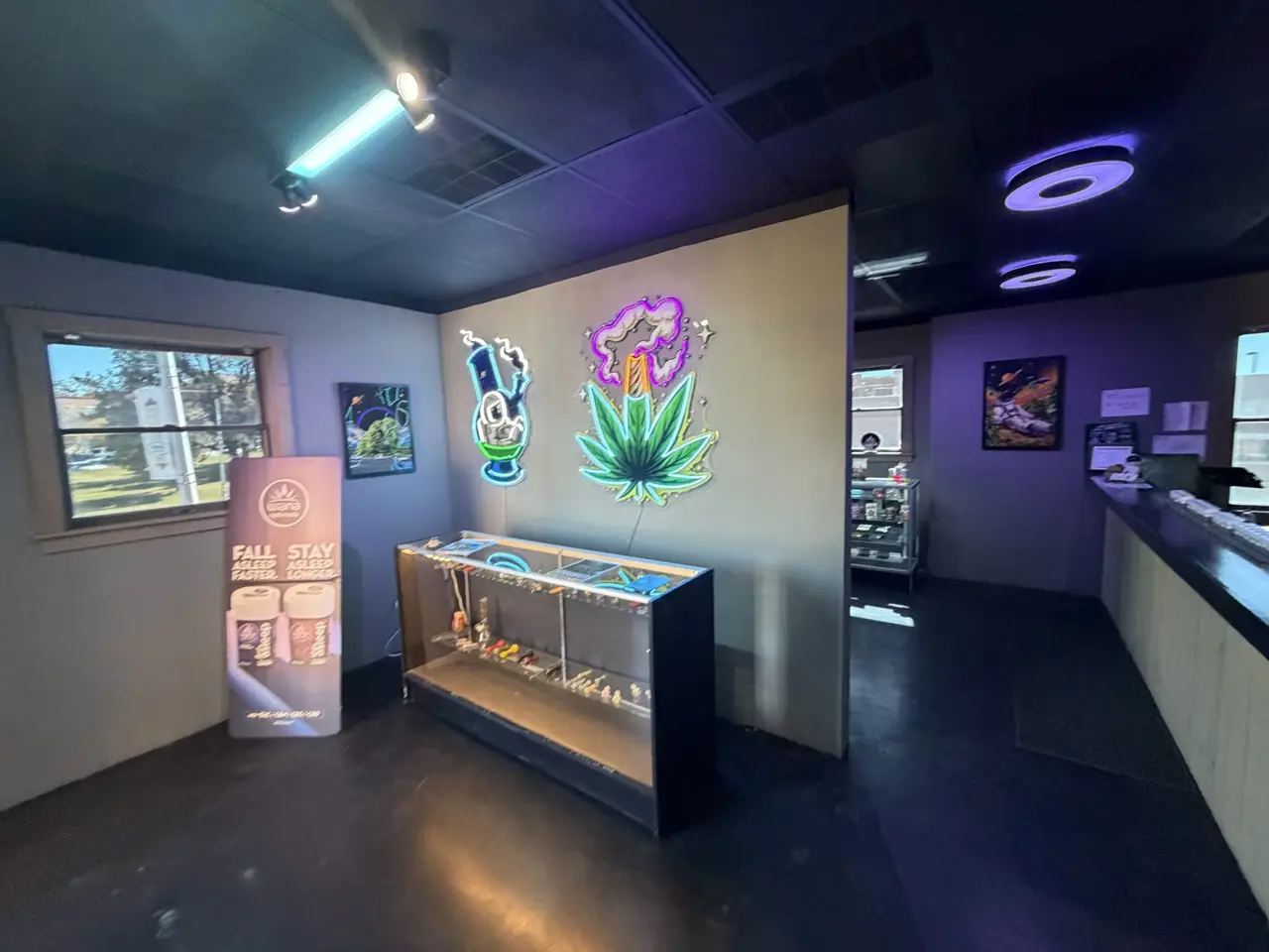 Neon signs over a lit glass case of glass pieces