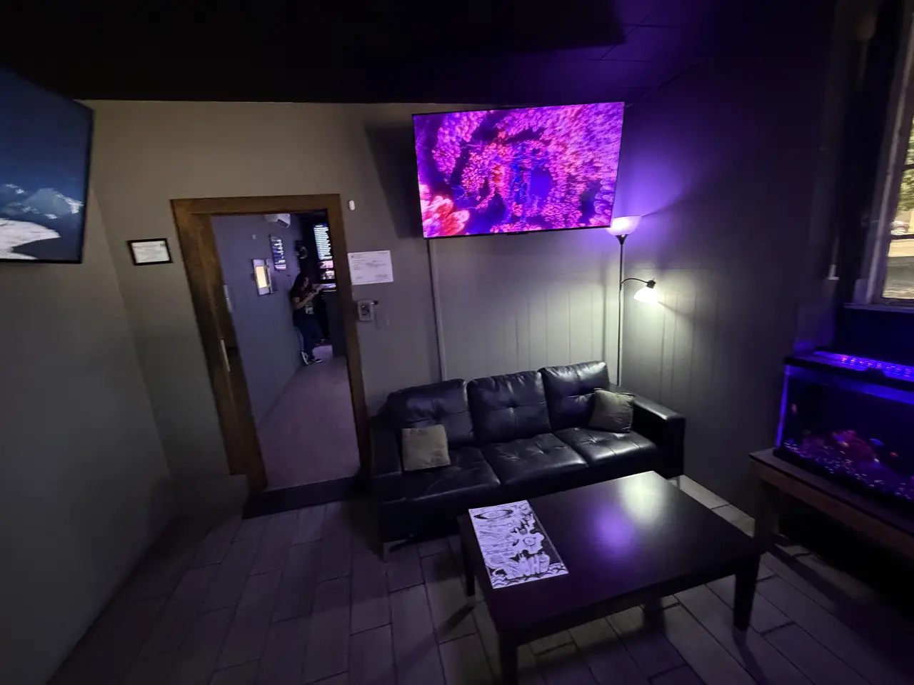 The waiting room: a black leather couch, a big screen with purple visuals, and the fish tank